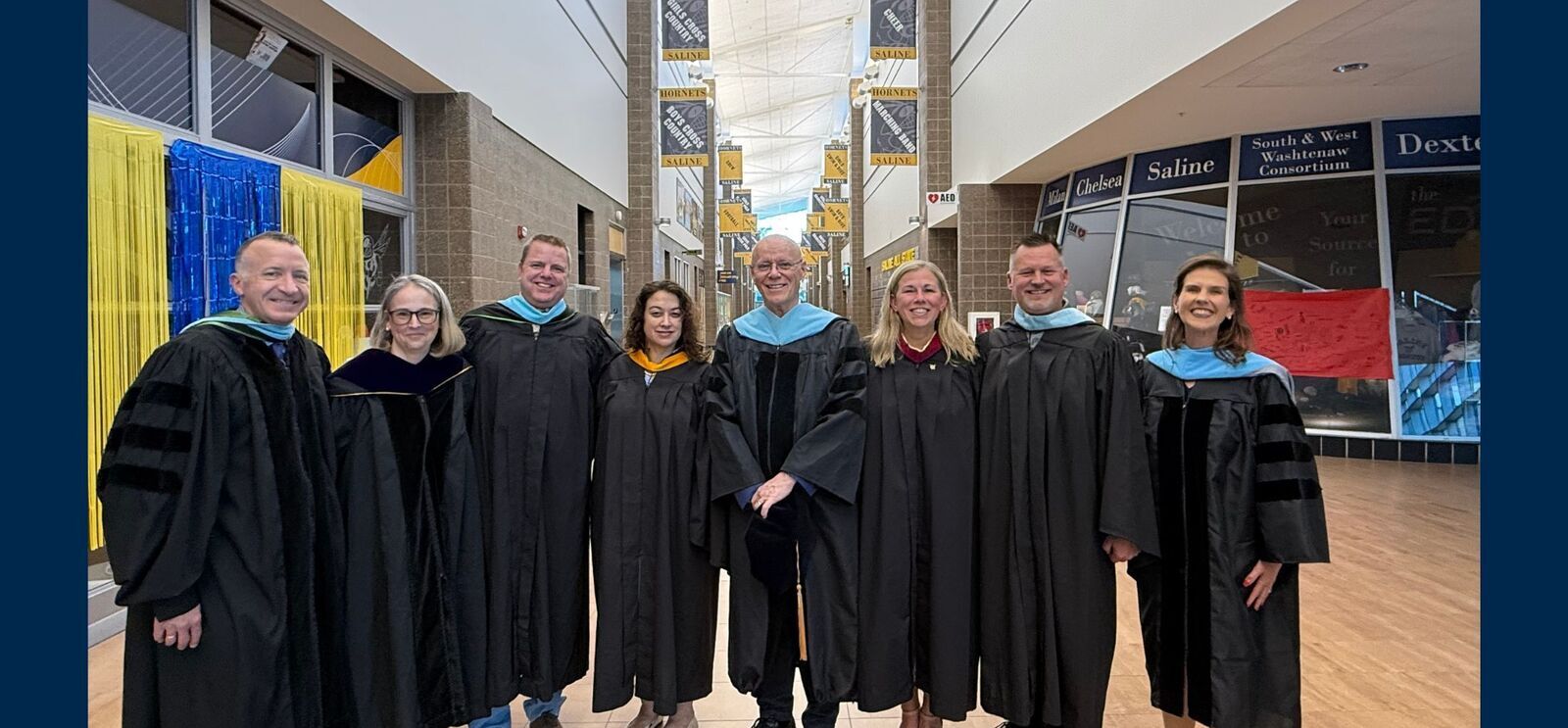 BOE trustees posing with incoming and outgoing superintendents in commencement regalia