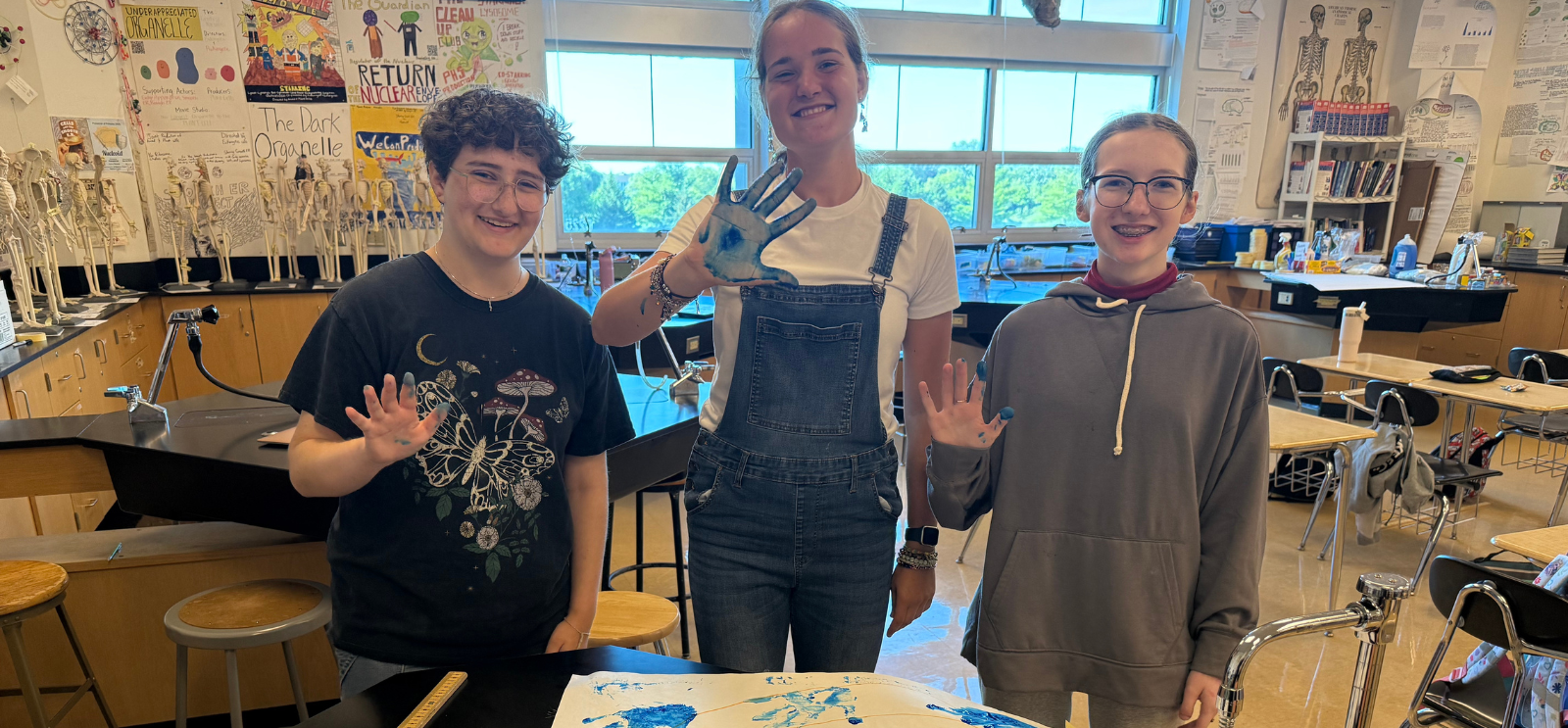 3 HS students with paint on their hand showing a high five
