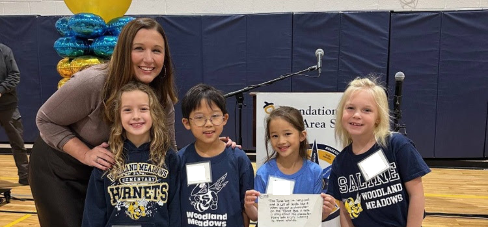 Teacher and students at a Foundation Event, standing with information